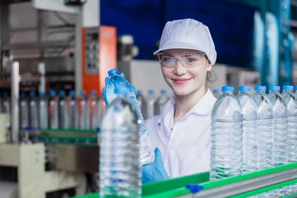 woman factory worker sterile uniform manufacture drink water. Female specialist factory line for processing and checking bottles water. Industrial product manufacturing aqua drink.