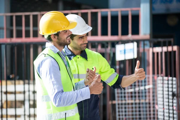 İnşaat alanında duran portre mühendisi. İnşaat teftişini işçiler denetliyor.