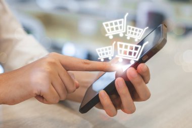 İnternetten akıllı telefon alışverişi yapan bir kadın, ekrandaki cep telefonunda alışveriş arabası simgesi. ödemeyi internetten al. çevrimiçi süpermarket aracı.