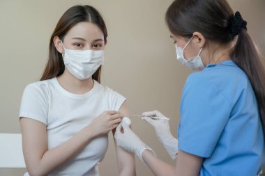 Maske takan kadın enfeksiyonu önlemek için bir doktor tarafından aşı oluyor. COVID-19 salgını sırasında. Kadın grip virüsü enfeksiyonuna karşı aşılanmış..