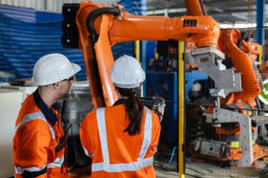 Makine mühendisi erkek ve kadın telsiz kullanarak makinelerin kalitesini kontrol ediyorlar. Fabrika endüstrisindeki servis programlama makineleri.