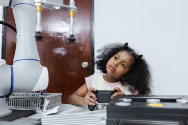 Çocuklar, Afrika kökenli Afro-Amerikalı kızlar joystick kullanıyor ve Afrika kökenli Amerikalı kızlar, sınıf odasında akıllı robot kolları kontrol ediyor. Elektrik sistemi eğitimi. Robot bilimi yenilik öğreniyor. BTMM eğitim kavramı.