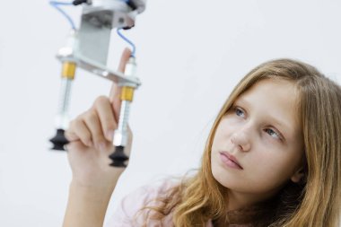 Kafkas eğitimi alan bir kız elektronik robot kolu sınıf odasındaki masada. Gelecekteki yapay zekalar için robot elektroniği öğreniyorum. Sistem becerisi eğitimi. BTMM eğitim kavramı.