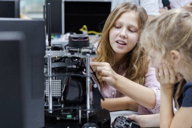 Beyaz bir kız, sınıf odasındaki masada elektronik robot eğitimi alıyor. Gelecekteki yapay zekalar için robot elektroniği öğreniyorum. Sistem becerisi eğitimi. BTMM eğitim kavramı.