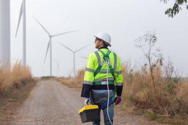 Güvenlik üniforması giyen mühendis adam rüzgar türbininin yenilenebilir enerji alanındaki operasyonel planlamayı tartışıyor. teknoloji çevreyi korur küresel ısınma sorunlarını azaltır.