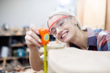 young carpenter women using measuring tape looking wood size at workspace. craftsman profession in wood factory. professional furniture woodwork.