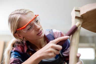 Genç marangoz kadın ahşap cilalama için zımpara kağıdı kullanıyor. Fabrika endüstrisi ahşap mobilya.