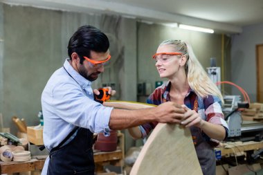 Genç marangoz ve kadınlar atölyede ahşap görünümlü mezura kullanıyorlar. Ahşap fabrikasında zanaatçılık mesleği.