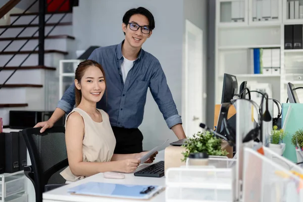 portrait asian business man and woman looking at camera standing at table office. company employee worker project report in modern office. Success team marketing.