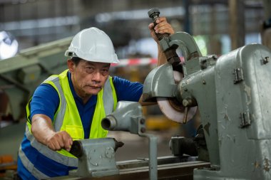 Yaşlı erkek işçi fabrikada çalışırken sert şapka giyer. İnsan teknisyenleri metal torna endüstrisini kontrol eder. iş fabrikası endüstriyel kavramı.