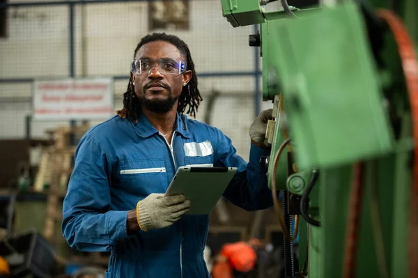 Ağır endüstri mühendisi profesyonel Amerikan Afrikalı işçi güvenlik üniforması giyiyor ve dijital tablet kullanıyor. Erkek yönetici sistem inşaatını kontrol ediyor.