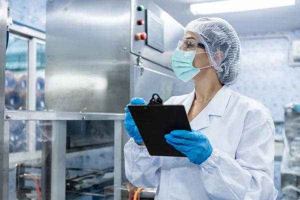 Kadın işçiler, suyu plastik şişelere doldurup tüketicilere götürmeden önce kaliteli içme suyunu kontrol ediyorlar. Fabrika üretim hattında su şişeleri.