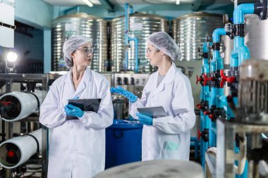 Fabrika üretim hattında kadın işçi. Şişelere su doldurma işleminden önce yönetim sistemi. Su ürünleri endüstrisi.