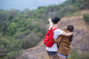 Mutlu Asyalı çift dağ macerası gezisinde sırt çantasıyla dolaşırken dikkatli olsun. Erkek ve dişi orman yolunda yürüyor doğa gezisi.