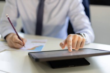 Ofiste dijital tablet kullanan bir iş adamı. erkek internet bilgi bağlantısını araştırıyor ve mesaj gönderiyor.