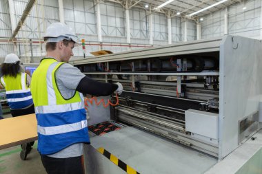 Personel çalışanı, kompresör hava üfleme silahı kullanarak makinedeki tozu temizliyor. Erkek temizlik makinesinin bölgeye ulaşması zor.