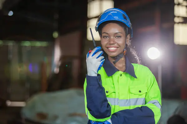 Industrial robotics engineer female american african holding walkie talkie looking at camera. woman technician modern factory 4.0, Technical supervisor of the robot operation department.