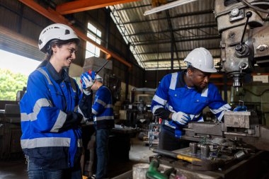 Üniforma giyen takım çalışanları fabrika endüstrisinde çalışıyor. Elinde telsiz işçi makinası olan bir kadın. Ağır sanayi konsepti.