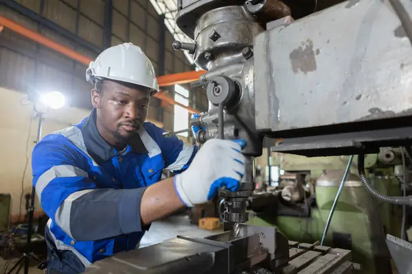 Male African American workers wearing uniform safety and hardhat working an iron cutting machine in factory Industrial. Engineering worker man work machine lathe metal. Heavy industry concept.