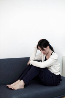 Kanepede yalnız oturan depresyonda bir kadın. Kadın baş ağrısı, mutsuz duygu. Depresyonda olan genç zihinsel sağlık sorunları.