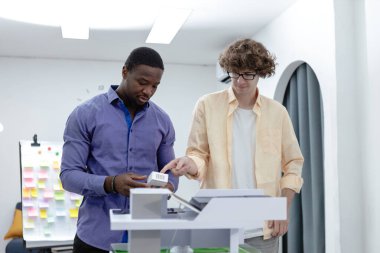 Takım çalışması mimarları, tasarımcılar masa üzerinde tasarımı olan bir ev modeli modern ofis kurma konusunda beyin fırtınası yapıyorlar. Bina tasarımı için çok ırklı şirket toplantısı.