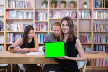 Elinde tablet yeşil ekran koma anahtarı bulunan iş kadını toplantı odasındaki sunum metni ve reklamı girerken kullanılacak. iş adamı yeşil ekran monitörü gösteriyor.