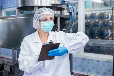 Kadın işçiler, suyu plastik şişelere doldurup tüketicilere götürmeden önce kaliteli içme suyunu kontrol ediyorlar. Fabrika üretim hattında su şişeleri.