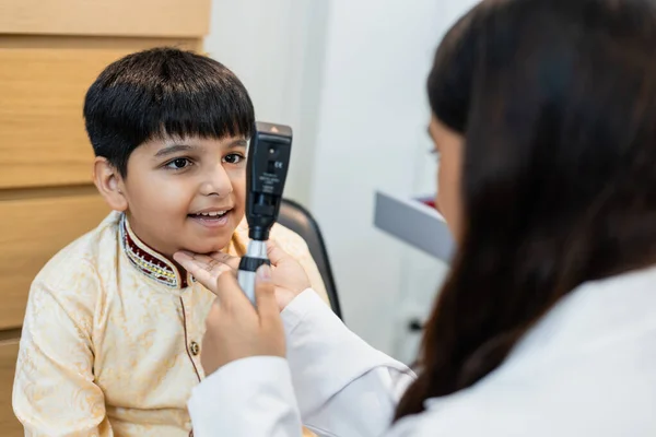 Indian child boy with women eye specialist examining eyesight modern ophthalmology equipment in clinic. Patient kid male checkup iris examines ophthalmological hospital. measure eyeglasses.