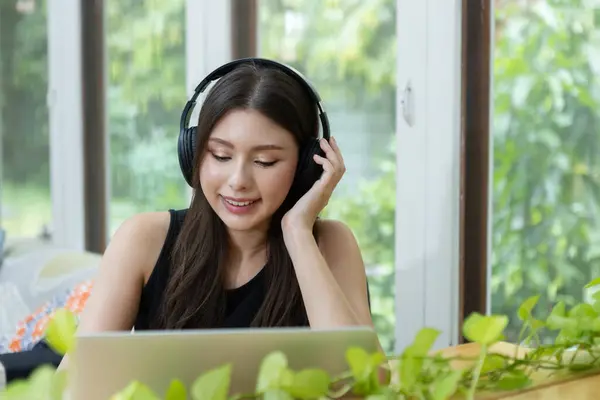 Female wear headphone using laptop at work, typing message or watch movies and listen to music. women freelancer working at home. Online meeting via video conference. chat communication studying.
