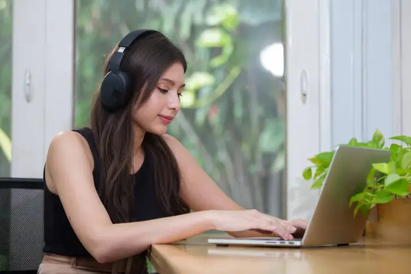 Female wear headphone using laptop at work, typing message or watch movies and listen to music. women freelancer working at home. Online meeting via video conference. chat communication studying.