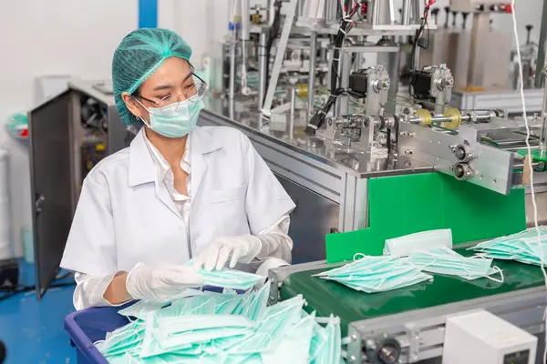 woman worker wear uniform are checking quality medical mask of manufacturer factory. face mask industry factory. manufacturer medical equipment.