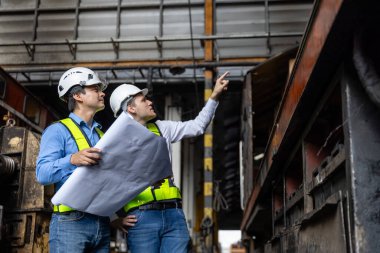 Ekip demiryolu mühendisi, onarım projesini teftiş edecek bakım merkezinde dizel motor. Teknisyen araç ve demiryolu sistemlerini kontrol etmeyi tartıştı.