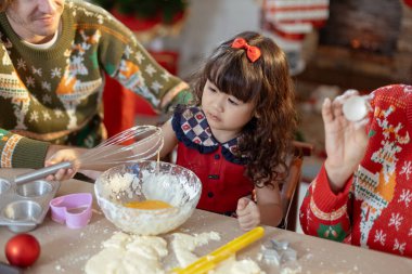 Küçük kız yemek masasında pasta pişirmekten zevk alıyor bayram şenlik aktivitelerinde. Mutlu aile noelleri. Ebeveynler ve kızları Noel 'i kendi evlerinde mutlu kutluyorlar.. 