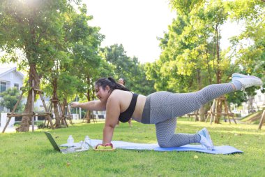 Asyalı kadın aşırı kilolu spor giyim egzersizi, dizüstü bilgisayarla önizlemede kilo vermek için. Kadın artı beden eğitimi, internette parkta yoga eğitimi. Sağlıklı kavram.