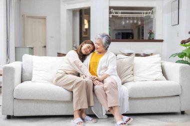 Anne ve kızı gülümsüyor. Oturma odasındaki koltukta mutlu bir aile olarak oturuyorlar. Birbirinize sevgi, ilgi, düşünce ve ilgi vermek, hayat sigortası reklamları ve sağlık kavramları..