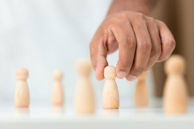 Tahta figürler takım çalışması için insan liderliği seçildi. İnsanların elleri, liderleri atamak için stratejiler geliştirmek için tahta kuklalar seçerler. Takım çalışması kavramının liderliği.
