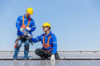 Teknisyenler, bir sanayi fabrikasının çatısına güneş paneli standartları kurup denetliyorlar. Doğadan elde edilen elektrik enerjisi güneş ışığı temiz yenilenebilir enerji.