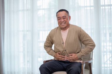 Asyalı yaşlı adam mide ağrısı çekiyor. Yaşlıların sağlık sorunları, konjenital hastalıklar, bel ağrısı. Emeklilik sağlıksız ve stresli.