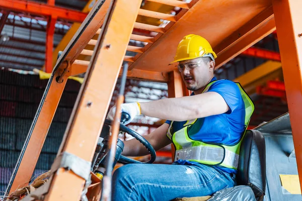 Worker wearing safety uniform drive forklift move product iron metal on shelves in warehouse. Two man engineer worker check stock stainless inspecting in storage logistic factory.