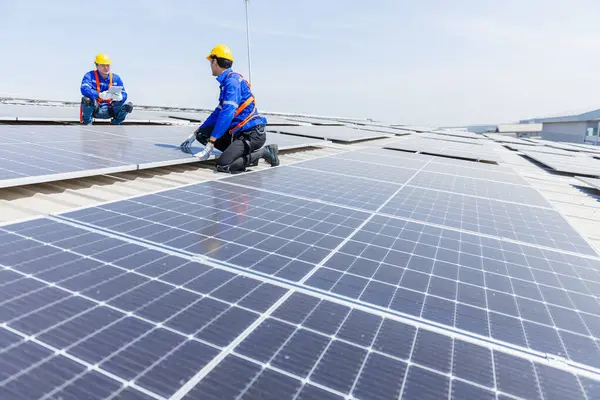 Technicians are installing and inspecting standards of solar panels on roof of an industrial factory. Electrical energy obtained from nature sunlight clean renewable energy.