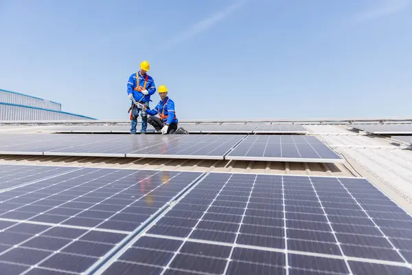 stock image Technicians are installing and inspecting standards of solar panels on roof of an industrial factory. Electrical energy obtained from nature sunlight clean renewable energy.