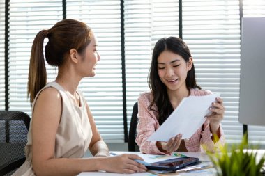 Asya 'daki iki kadın işletme bürosu mali muhasebe evraklarını tartışıyor şirket kârı üzerinde çalışıyor, kadın yöneticinin beyin fırtınası yapıyor belge finansmanını inceliyor.