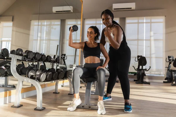 women African American plus-size coach training latina female dumbbell lifts weights exercise in gym. sport training weights fitness, Exercise to lose weight, take care of health.