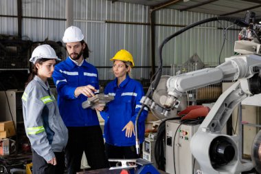 Uzaktan kumanda kullanan bir ekip mühendisi otomasyon robotu silah makinesinin başında duruyor. teknisyen bakım robot atölyesi.