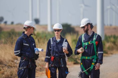 Ekip mühendisi rüzgar türbini işçi üniforması güvenlik anketi operasyon planlama yel değirmeni temiz enerjisini tartışıyor. Alternatif teknoloji çevreyi korur küresel ısınma sorunlarını azaltır.