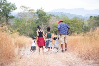 Dikiz aynası. Mutlu karışık ırk ailesi, baba ve çocuklar seyahat eder ve kamp yapar altın çayırlarda yürür, seyahat konsepti.