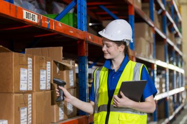 Sarışın kadın saç fabrikası çalışanı. Depodaki ürün raflarındaki ürün sayısını tarıyor. Lojistik ve dağıtım işinde çalışan bir kadın. İthalat-ihracat deposu.