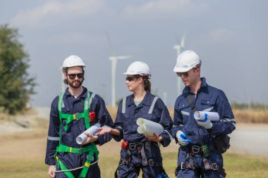 Ekip mühendisi rüzgar türbini işçi üniforması güvenlik anketi operasyon planlama yel değirmeni temiz enerjisini tartışıyor. Alternatif teknoloji çevreyi korur küresel ısınma sorunlarını azaltır.