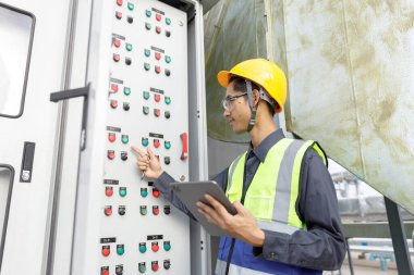 Elektrik mühendisi, santral ana Dağıtım Tahtaları kontrol paneli elektrik fabrikası binasını kontrol ediyor. Erkek Endüstriyel Teknisyen, güç dağıtım odasında çalışıyor..