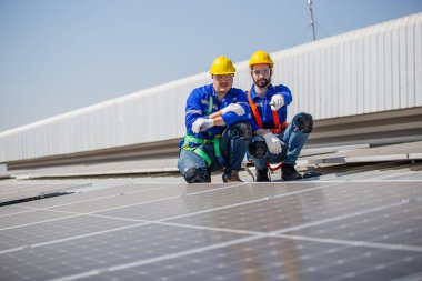 Mühendisler, bir sanayi fabrikasının çatısına güneş panelleri kurup denetlemeyi ayarlıyorlar. Ekip teknisyeni güneş pilini kontrol edip tamir ediyor. Alternatif yenilikçi güç çevresi.